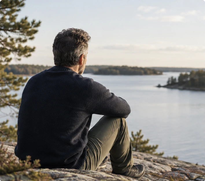 Man som sitter på en klippa och blickar ut över vattnet